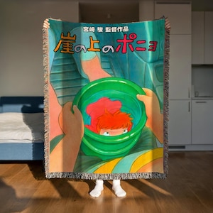 A person is holding up a colorful blanket with an illustration of a character from the animated film "My Little Pony".