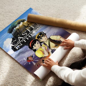 A person is holding a poster of the animated film "Castle in the Sky" and appears to be unfolding it.