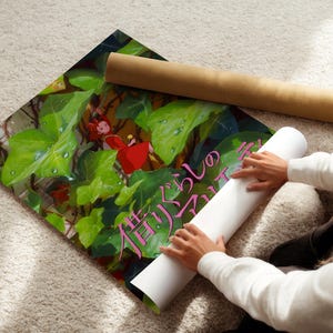 A person is holding a roll of paper and placing it on a colorful poster with a green background and a red character.