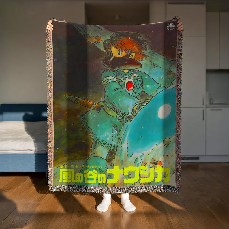 A person is holding up a colorful, illustrated poster featuring a character with a large head and a sword, set against a cosmic background.
