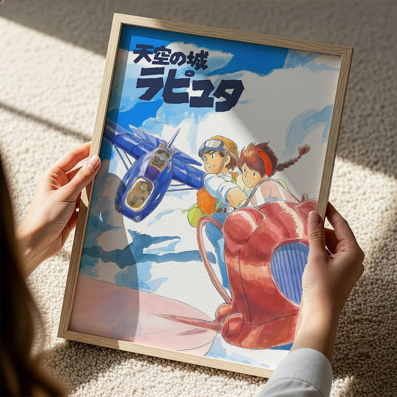 A person is holding a framed picture of an animated scene featuring a blue airplane and two characters, one of whom is wearing a helmet.