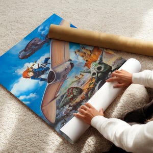 A person is sitting on the floor, holding a roll of paper and unfolding a large poster featuring an illustration of a character and a spaceship.