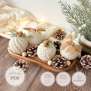 May include: Four cream-colored crocheted spheres decorated with tan satin ribbons, small pinecones, and wooden beads. The spheres are arranged on an oval wooden tray alongside additional pinecones and a sprig of greenery.