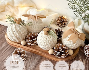 May include: Four round, cream-colored crocheted ornaments decorated with tan satin ribbons, small pinecones, and wooden beads. The ornaments are arranged on an oval wooden tray. Text on the image includes PDF Pattern, English Language (US Terms), Human Designed (no AI), and KreAtelier.