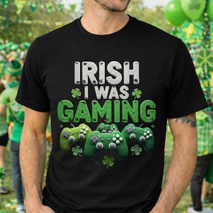 Puede incluir: Camiseta negra con el texto "IRISH I WAS GAMING" en blanco y verde, con mandos de juego verdes y tréboles. Un diseño divertido para el Día de San Patricio y los gamers.