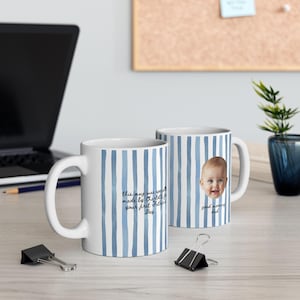 Op de afbeelding: Twee witte keramische mokken met blauwe verticale strepen. E&eacute;n mok heeft een babygezicht en de woorden "good morning dad". De andere mok heeft de tekst "this mug was specially made by Charlotte for your first Father's Day."