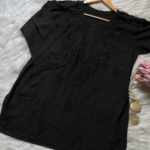 Pu&ograve; includere: Top tunica nero con ricami floreali intricati sul davanti e sulle maniche. Il top ha uno scollo tondo e maniche a tre quarti. Il ricamo aggiunge un tocco di eleganza. Realizzato in tessuto morbido.