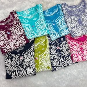 May include: A collection of eight long-sleeved tunics in various colours including maroon, turquoise, blue, lavender, black, lime green, navy, and pink. Each tunic features a white floral embroidery pattern around the neckline and front.