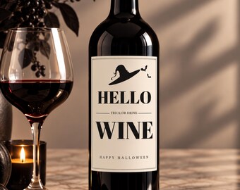 Może przedstawiać: Ciemna szklana butelka wina z kremową etykietą przedstawiającą czarny kapelusz czarownicy, nietoperze oraz napis HELLO TRICK OR DRINK WINE HAPPY HALLOWEEN. Obok butelki stoi kieliszek wypełniony czerwonym winem oraz mała czarna świeca.
