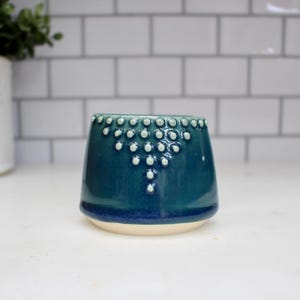 K&ouml;nnte beinhalten: Ein Set aus drei Keramikbechern mit gesprenkelter, matter Oberfl&auml;che. Jeder Becher hat eine andere Farbe: hellblau, cremefarben und grau. Die Becher haben ein schlichtes, modernes Design, geeignet f&uuml;r Kaffee oder Tee.