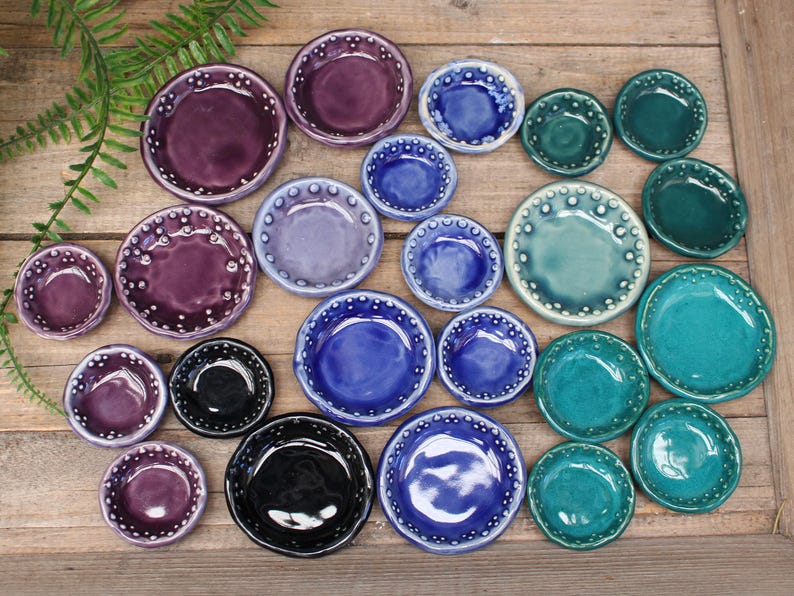 May include: A set of three ceramic mugs with a speckled, matte finish. The mugs are in shades of cream, light gray, and dark gray. Each mug has a simple, minimalist design, perfect for coffee or tea.