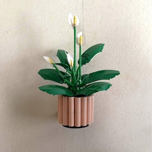 Könnte beinhalten: Eine weiße Keramiktasse mit schwarzem Henkel und dem Text "But First, Coffee" in fetter, schwarzer Schrift. Die Tasse steht vor einem verschwommenen Hintergrund, der eine gemütliche Umgebung suggeriert.