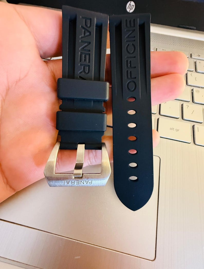 May include: Black rubber watch strap with the brand name "PANERAI" embossed on one strap and "OFFICINE" on the other. The strap features a silver-colored buckle.