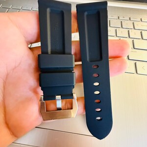 May include: Two dark blue watch straps with a silver buckle. One strap has a series of holes for adjustment. The straps are made of a flexible material and are designed to attach to a watch face.
