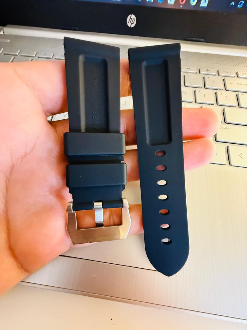 May include: Two dark blue watch straps with a silver buckle. One strap has a series of holes for adjustment. The straps are made of a flexible material and are designed to attach to a watch face.