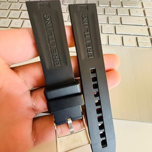 Puede incluir: Dos correas de reloj Breitling negras. Una correa tiene una hebilla plateada y la otra tiene orificios de ajuste. Las correas est&aacute;n marcadas con el logotipo de Breitling y el tama&ntilde;o 22-20 o 22-21.