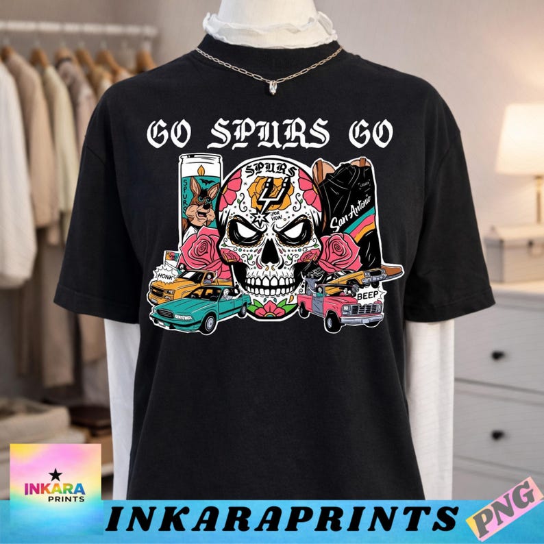 May include: Black t-shirt with the text "GO SPURS GO" above a colorful sugar skull design. The design includes roses, cars, and a candle. The shirt also features the text "INKARAPRINTS" at the bottom.