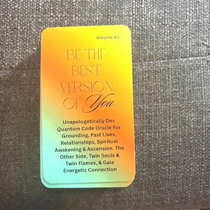 May include: A deck of oracle cards with a gradient yellow to green background. The text on the card reads "BE THE BEST VERSION OF You" and "Volume #3". Additional text describes the oracle's focus on grounding, past lives, relationships, and spiritual awakening.