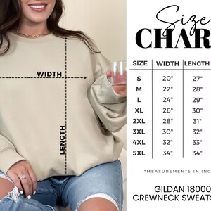 K&ouml;nnte beinhalten: Beiges Gildan 18000 Crewneck-Sweatshirt mit Gr&ouml;&szlig;entabelle. Die Tabelle zeigt Ma&szlig;e in Zoll f&uuml;r Breite, L&auml;nge und &Auml;rmell&auml;nge, von Gr&ouml;&szlig;e S bis 5XL. Das Sweatshirt wird von einer Person getragen.