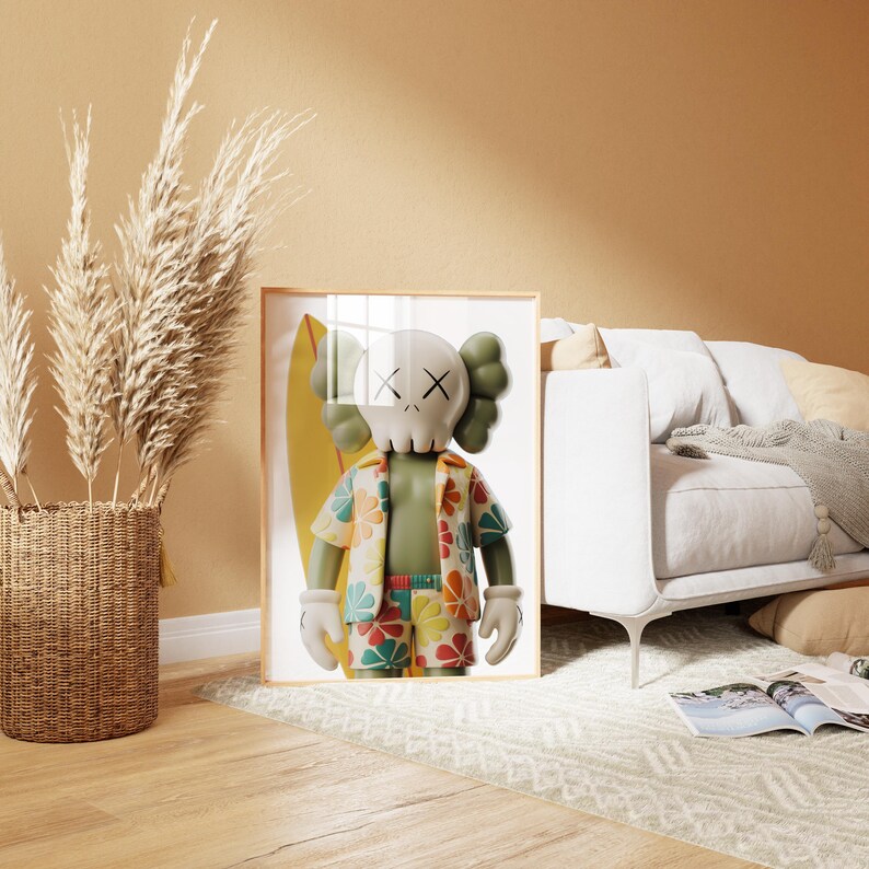 May include: Framed artwork featuring a cartoon figure with a skull-like head, wearing a Hawaiian shirt and shorts, and holding a surfboard. The figure is in front of a yellow surfboard. The artwork is in a light wood frame.