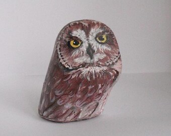 Pode incluir: Estatueta de coruja de pedra pintada à mão. A coruja é principalmente bordô com detalhes brancos e castanhos. Possui grandes olhos amarelos e um padrão de penas detalhado. Um item decorativo único.