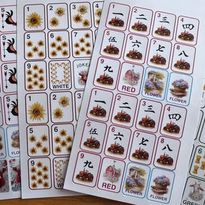 May include: Sheets of stickers featuring various designs, including roosters, sunflowers, and Chinese characters. The stickers have a white background with red, blue, and green accents. Some stickers have the words "RED", "FLOWER", and "WHITE".