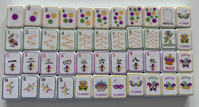 May include: A collection of white Mahjong tiles with various symbols, numbers, and characters. The tiles feature purple, green, and gold accents, along with images of a pelican, trumpets, and a crown. Some tiles have the words "WHITE", "GREEN", "RED", and "JOKER".