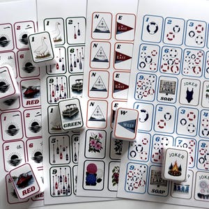 May include: A collection of nautical-themed stickers and game cards. The cards feature images of boats, compasses, and life preservers. Some cards have the words "RED" and "GREEN". The stickers have images of geese, flowers, and a campfire.