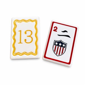 Peut inclure: Deux tuiles de jeu rectangulaires. Une tuile blanche porte le chiffre 13 en or dans un cadre festonn&eacute; dor&eacute;. L'autre tuile a un bord rouge, le chiffre 2 et un &eacute;cusson avec des &eacute;toiles et des rayures.