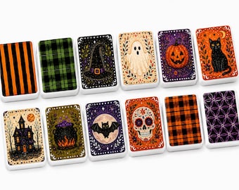 May include: A set of twelve rectangular tiles featuring various Halloween-themed illustrations, including a black cat, a pumpkin, a ghost, a witch hat, a skull, a bat, a haunted house, a cauldron, and several orange, black, and green patterns.