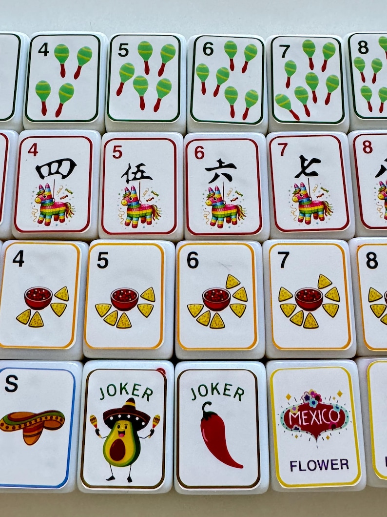 以下が含まれることがあります： 様々なカラフルなイラストが描かれた白いゲームタイル。タイルには数字、マラカス、ピニャータ、サルサとチップス、ソンブレロが描かれています。一部のタイルには「JOKER」と「MEXICO」の文字が書かれています。