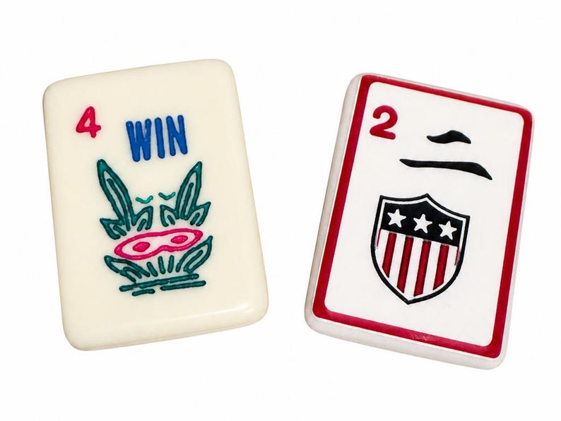 Peut inclure: Deux tuiles rectangulaires de Mahjong. L'une porte le chiffre 4, le mot "WIN" et un motif vert et rose. L'autre affiche le chiffre 2, un symbole noir et un &eacute;cusson bord&eacute; de rouge avec des &eacute;toiles et des rayures.