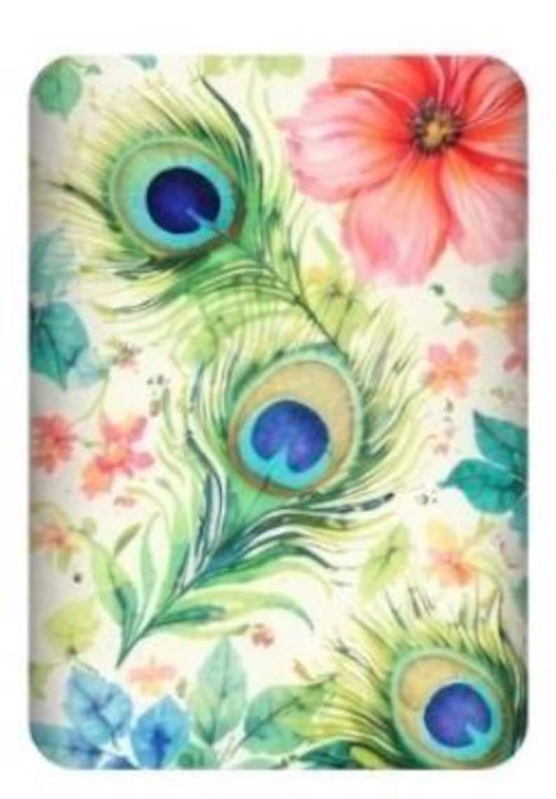 May include: A decorative item featuring a watercolor design of peacock feathers, flowers, and foliage. The feathers have blue and teal accents, with a large pink flower in the upper right corner. The background is a cream color.