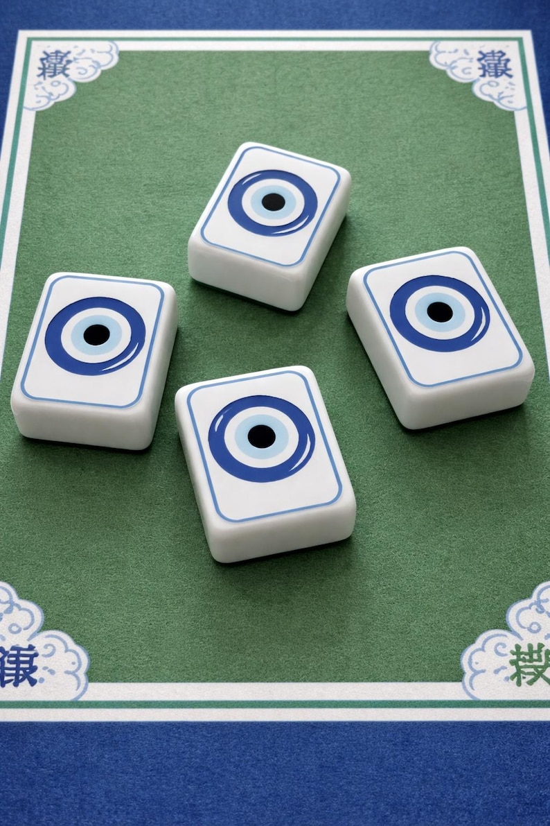 May include: Four white rectangular game tiles with a blue eye design on a green surface. The eye design features a blue outline, a blue iris, and a black pupil. The tiles are arranged on a green surface with a blue border.