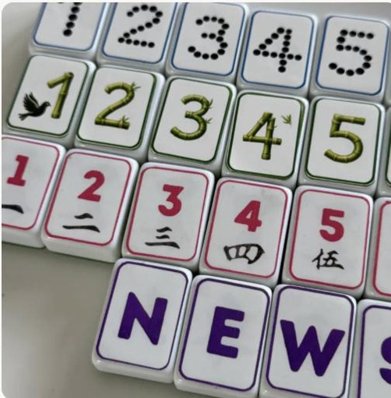 Peut inclure: Gros plan sur des tuiles de Mahjong blanches avec divers symboles et chiffres. Les tuiles pr&eacute;sentent des points noirs, des chiffres rouges, des chiffres verts en forme de bambou et le mot "NEW" en violet. Les tuiles sont dispos&eacute;es en grille.