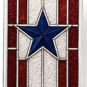 May include: A rectangular decorative item with a patriotic theme. It has a blue star at the centre, with red and white sections, all within a silver frame. The design is reminiscent of a stained-glass window.