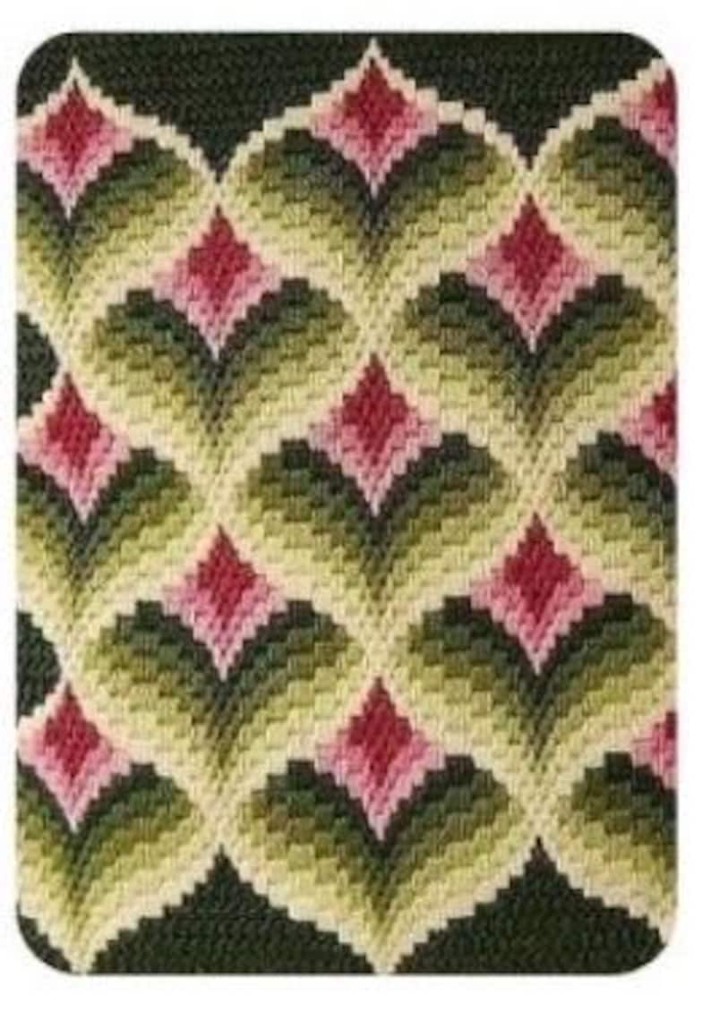 May include: A rectangular needlepoint design featuring a repeating pattern of stylized floral motifs. The design uses shades of green, pink, and cream against a dark background. The pattern is symmetrical, with each element resembling a stylized leaf or petal.
