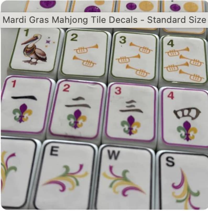 Peut inclure: Gros plan sur plusieurs tuiles de Mahjong blanches avec des d&eacute;calcomanies sur le th&egrave;me du Mardi Gras. Les tuiles pr&eacute;sentent des chiffres, des trompettes et des motifs de fleur de lys en vert, violet et or. Le texte "Mardi Gras Mahjong Tile Decals - Standard Size" est visible.