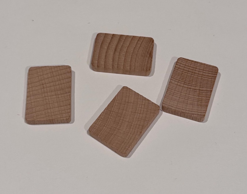Puede incluir: Cuatro bloques de madera rectangulares con esquinas redondeadas. Los bloques son de color marr&oacute;n claro y muestran la veta natural de la madera. Los bloques est&aacute;n dispuestos sobre una superficie blanca.