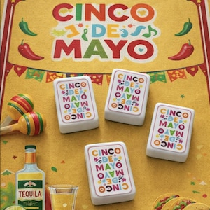 Peut inclure: Image sur le thème de Cinco de Mayo avec un fond jaune et le texte "Cinco de Mayo". L'image comprend des maracas, de la tequila, un verre à shot, des tacos et des cartes décoratives avec le même texte. Des piments rouges et verts et une tranche de citron vert sont également visibles.