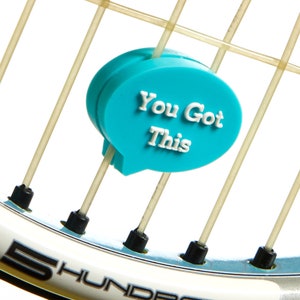 May include: A turquoise blue tennis racket charm with the text "You Got This" in white lettering.