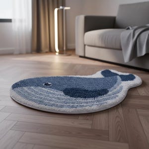 Könnte beinhalten: Ein blau-weißer Wal-Teppich. Der Teppich zeigt einen dunkelblauen Walkörper mit helleren blauen und weißen Akzenten. Der Teppich besteht aus einem weichen, strukturierten Material und ist für den Hausgebrauch bestimmt.