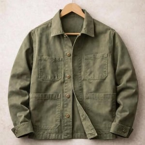 May include: An olive green utility jacket featuring a classic collar, long sleeves with buttoned cuffs, and a front button closure. The garment includes two chest pockets and two larger lower pockets, all constructed from a durable, solid-coloured fabric.