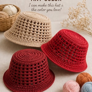 May include: Three crochet bucket hats in beige, red, and burgundy, with a basket of yarn balls in the background. The hats have a distinctive open weave design. Text on the image reads "MADE IN ANY COLOR" and "I can make this hat in the color you love!"