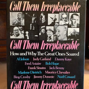 May include: A black book cover with the title "Call Them Irreplaceable" in pink script. The cover features black and white photos of entertainers, with names like Frank Sinatra and Judy Garland. The text "How and Why The Great Ones Soared" is also visible.
