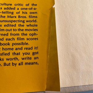 以下が含まれることがあります： 本のページのクローズアップ。左ページは黄色で、"pastoral treatise"や"Marx Bros. films"などの黒いテキストが含まれています。右ページはオフホワイトです。本の端が見えます。
