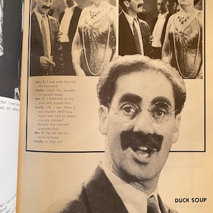 以下が含まれることがあります： 映画「Duck Soup」からの白黒画像。フォーマルな服装の俳優が登場。メガネと大きな口ひげの男性に焦点が当てられています。映画からのテキストも表示されています。