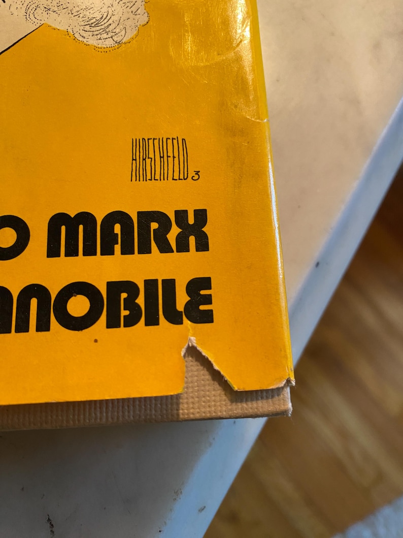 以下が含まれることがあります： 大きな黒い文字で「O Marx」というタイトルが書かれた本の表紙のクローズアップ。表紙は黄色で、タイトルの上に「HIRSCHFELD」という名前が印刷されています。本の角が少し破損しています。