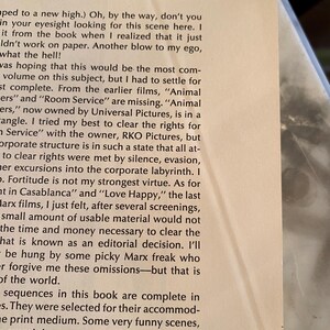 以下が含まれることがあります： 黒いテキストが書かれた本のページをクローズアップ。テキストは映画の権利、欠落したシーン、著者が本を完成させる上での課題について議論しています。ページはわずかに傾いています。