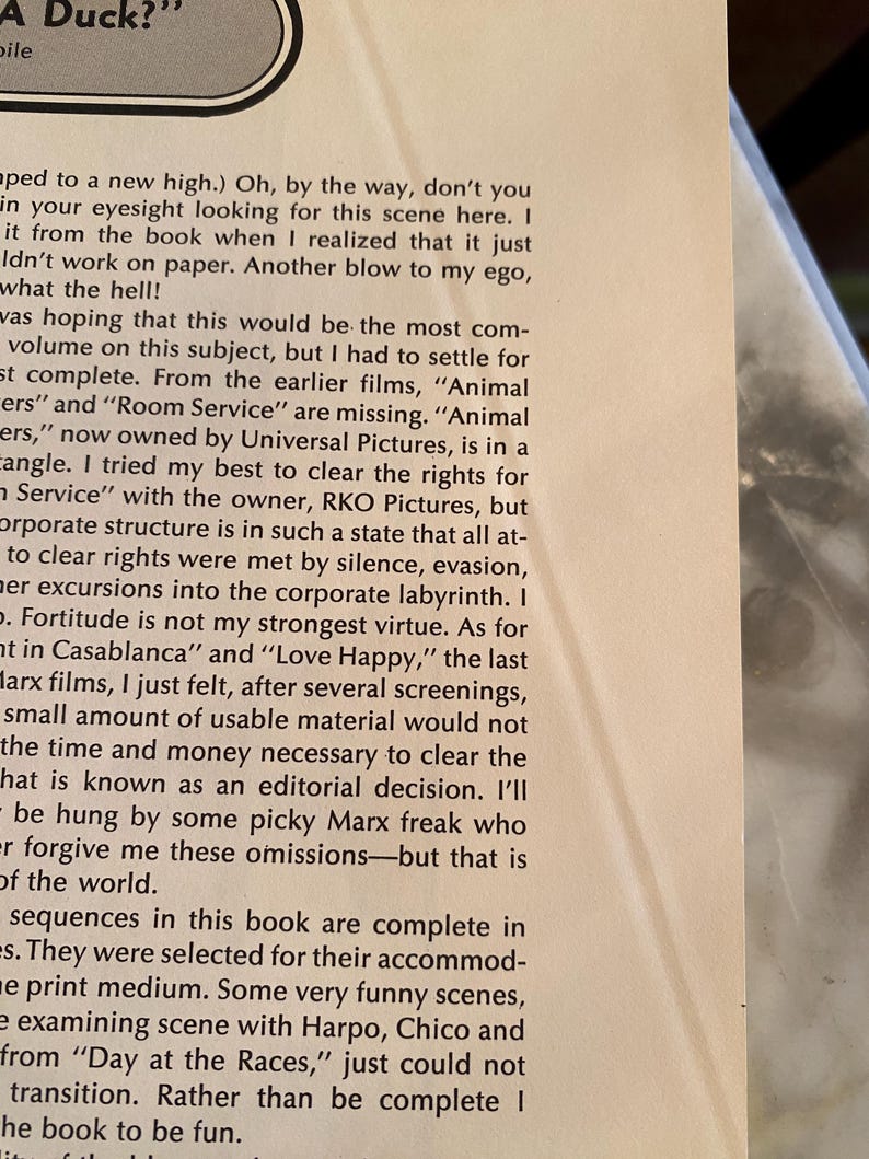 以下が含まれることがあります： 黒いテキストが書かれた本のページをクローズアップ。テキストは映画の権利、欠落したシーン、著者が本を完成させる上での課題について議論しています。ページはわずかに傾いています。